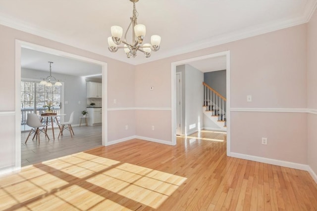 spare room featuring an inviting chandelier, crown molding, and hardwood / wood-style floors