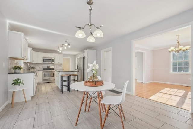 dining room with sink, a notable chandelier, and light hardwood / wood-style floors