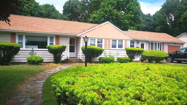 ranch-style house with a shingled roof and a front lawn