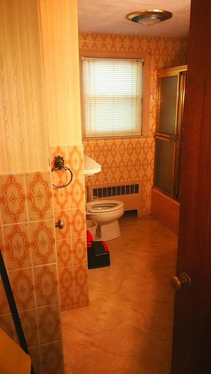 bathroom with radiator, a shower stall, and toilet