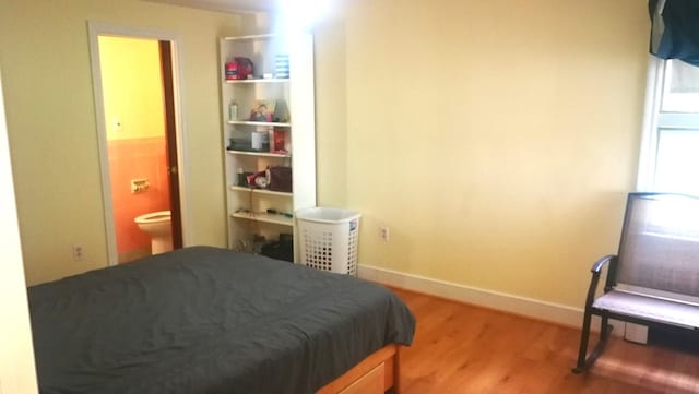 bedroom featuring connected bathroom, baseboards, and wood finished floors