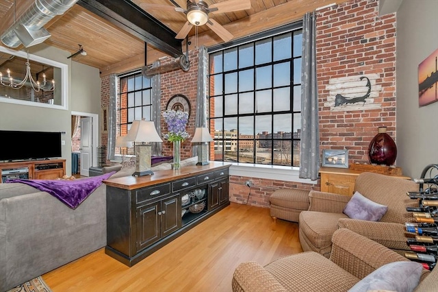 sitting room with light wood-type flooring, wood ceiling, brick wall, ceiling fan with notable chandelier, and beam ceiling