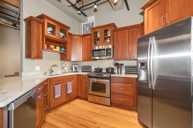 kitchen featuring sink, light hardwood / wood-style flooring, light stone counters, kitchen peninsula, and stainless steel appliances