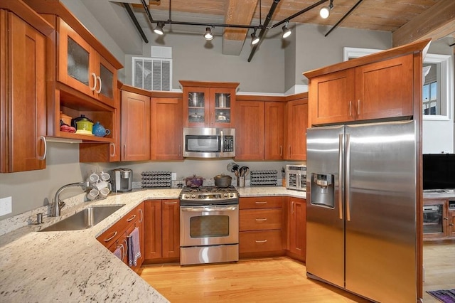 kitchen featuring light stone counters, sink, stainless steel appliances, and light hardwood / wood-style floors