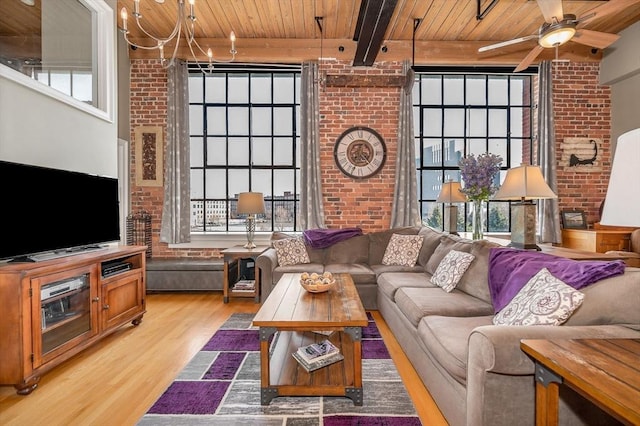 living room featuring ceiling fan, light wood-type flooring, beam ceiling, wood ceiling, and brick wall