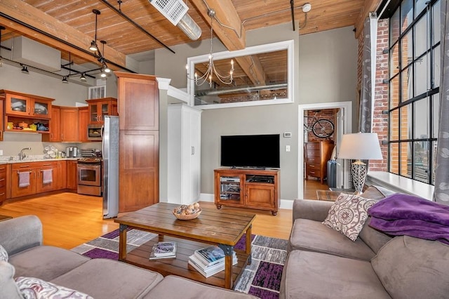 living room featuring sink, wooden ceiling, an inviting chandelier, light hardwood / wood-style flooring, and beamed ceiling