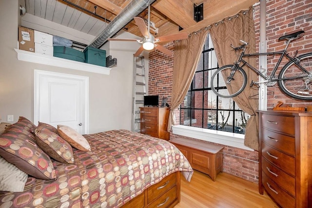 bedroom with ceiling fan, wooden ceiling, beamed ceiling, brick wall, and light wood-type flooring