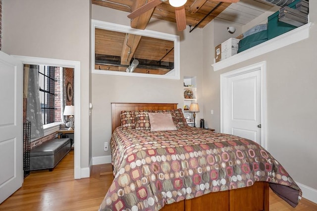 bedroom featuring beam ceiling, light hardwood / wood-style flooring, ceiling fan, and wood ceiling