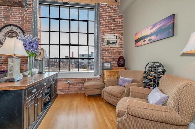 living area with light hardwood / wood-style flooring and brick wall