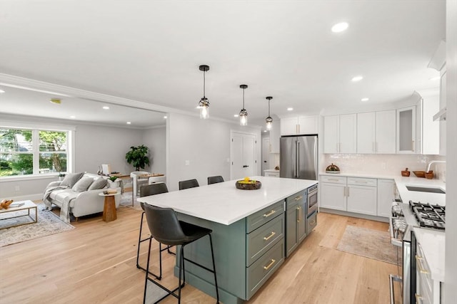 2 Suncrest Ave, Wilmington, MA 01887 - kitchen with stainless steel appliances, white cabinets, a kitchen island, a kitchen bar, and light countertops
