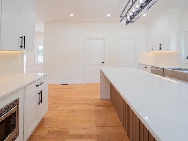 28 Berkshire Ave, Sharon, MA 02067 - kitchen with light wood-style floors, appliances with stainless steel finishes, white cabinetry, light stone counters, and recessed lighting