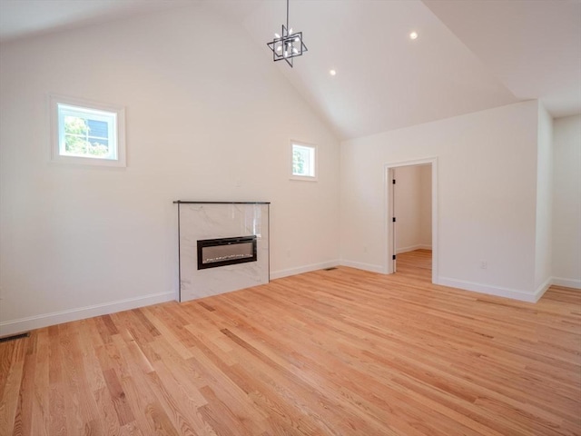 28 Berkshire Ave, Sharon, MA 02067 - unfurnished living room with light wood-type flooring, a glass covered fireplace, high vaulted ceiling, recessed lighting, and a chandelier