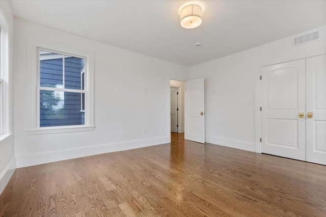 unfurnished bedroom with baseboards, wood finished floors, and a closet