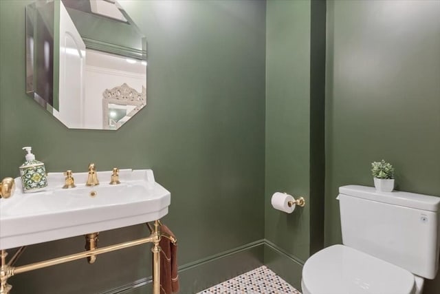 bathroom with toilet, baseboards, and a sink