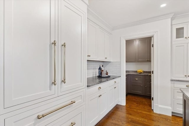 kitchen with white cabinets, crown molding, decorative backsplash, dark wood-type flooring, and dark stone counters