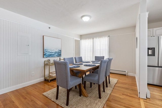 dining area with light wood finished floors, baseboard heating, electric panel, and baseboards