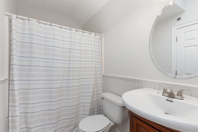 bathroom with toilet, wainscoting, lofted ceiling, and vanity