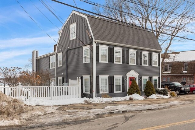 view of front of property with a shingled roof, fence private yard, and a gambrel roof