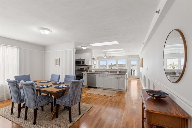 dining room with a skylight, light wood-style floors, and a wealth of natural light