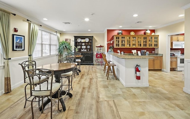 kitchen with a kitchen breakfast bar, light stone countertops, white appliances, and ornamental molding