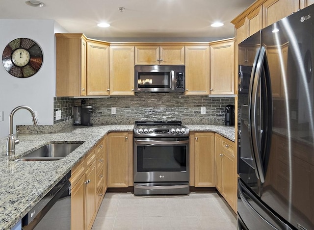 kitchen with decorative backsplash, appliances with stainless steel finishes, light stone counters, and sink