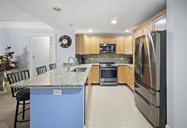 kitchen featuring sink, stainless steel appliances, light stone counters, kitchen peninsula, and a breakfast bar area