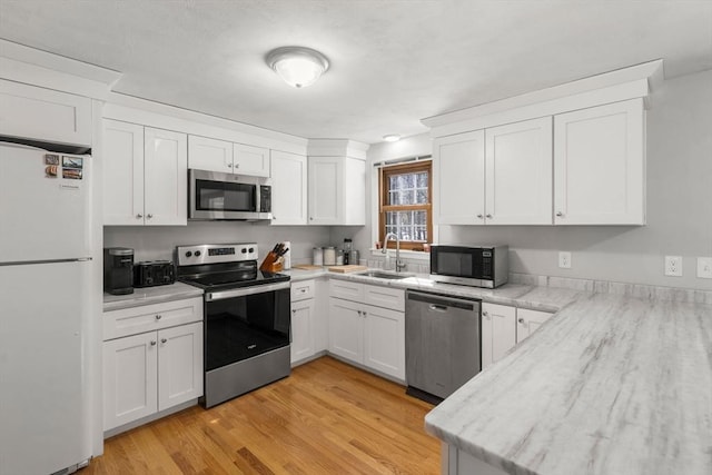 kitchen with appliances with stainless steel finishes, a sink, and white cabinetry