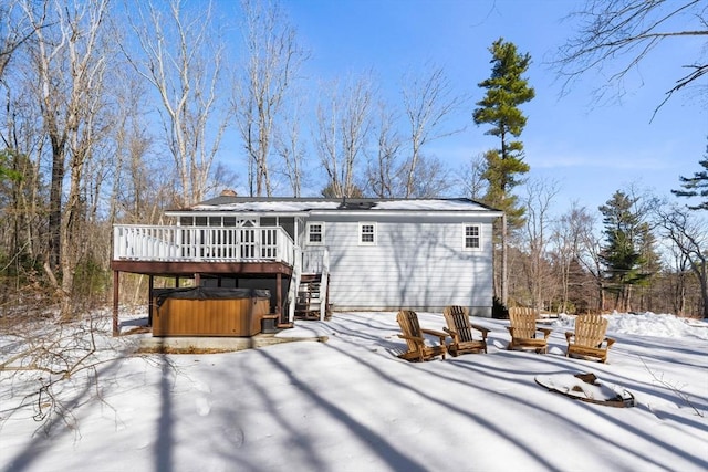 snow covered back of property featuring a wooden deck, a sunroom, and a hot tub