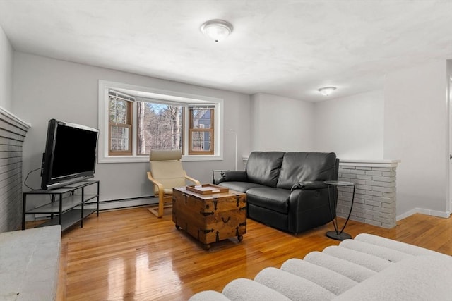 living room featuring a baseboard heating unit, baseboards, and wood finished floors