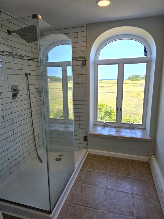 bathroom featuring plenty of natural light, baseboard heating, and walk in shower