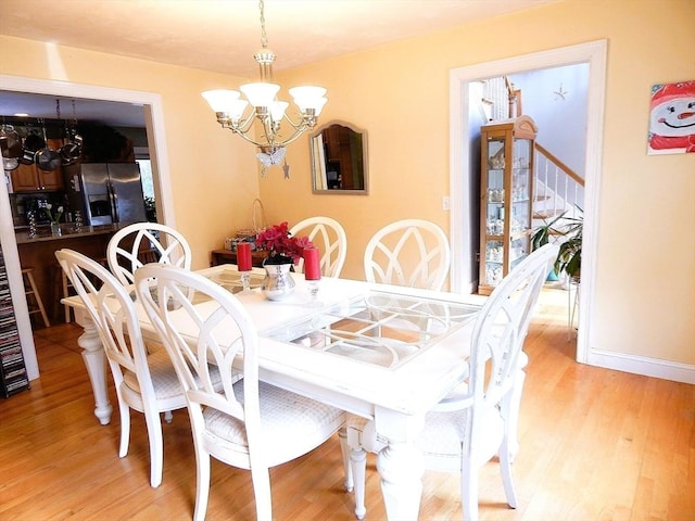 dining space with a notable chandelier and light hardwood / wood-style floors