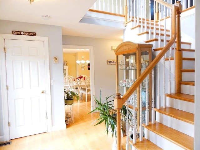 staircase with wood-type flooring and an inviting chandelier