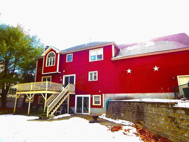 snow covered rear of property with a wooden deck