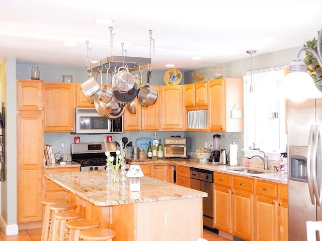 kitchen featuring a kitchen island, appliances with stainless steel finishes, sink, light stone counters, and light brown cabinets