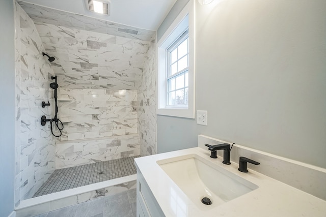 bathroom with a tile shower and vanity