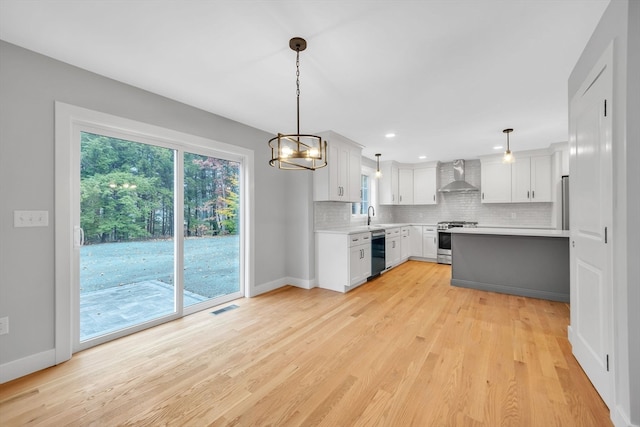 kitchen featuring wall chimney range hood, pendant lighting, and plenty of natural light