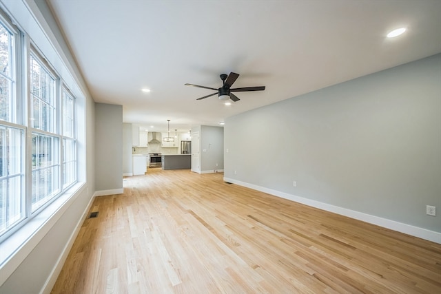 unfurnished living room with ceiling fan, light hardwood / wood-style floors, and plenty of natural light