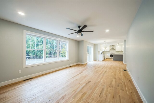 unfurnished living room with light hardwood / wood-style flooring and ceiling fan