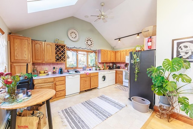 kitchen featuring a skylight, ceiling fan, backsplash, white appliances, and washer / dryer