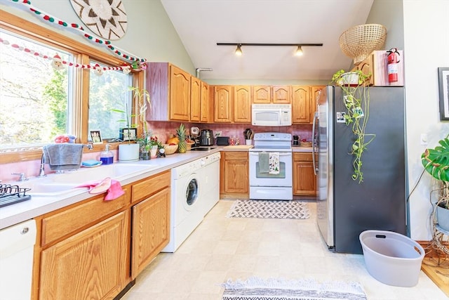 kitchen with sink, tasteful backsplash, washer / clothes dryer, vaulted ceiling, and white appliances