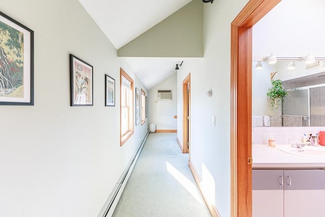 hallway with lofted ceiling, a baseboard heating unit, sink, light colored carpet, and a wall unit AC