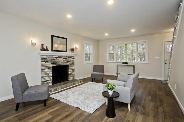 living area featuring a brick fireplace, baseboards, wood finished floors, and recessed lighting