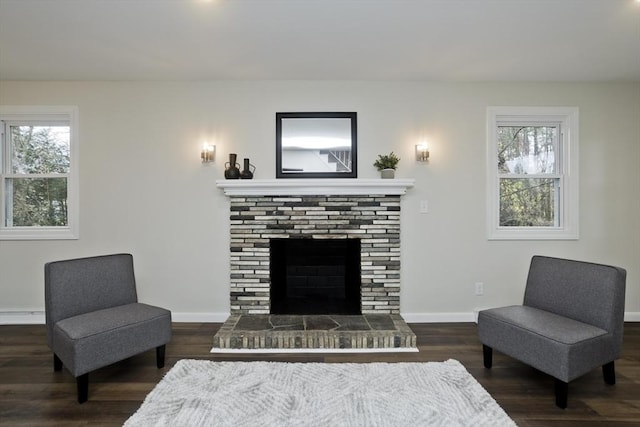 living area with a brick fireplace, baseboards, and wood finished floors