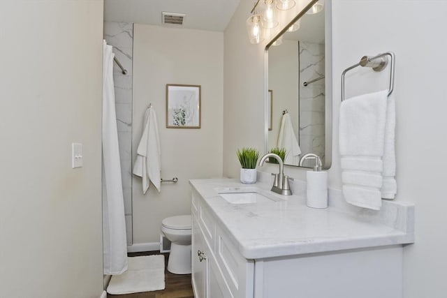 full bathroom featuring baseboards, visible vents, toilet, wood finished floors, and vanity