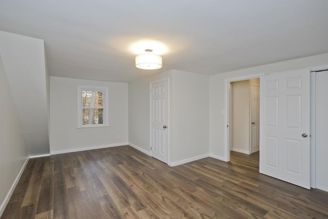 unfurnished room featuring baseboards and dark wood-type flooring