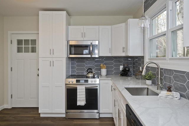 kitchen featuring light stone countertops, appliances with stainless steel finishes, white cabinets, and a sink