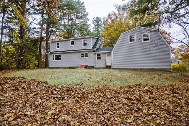 rear view of house with entry steps, a yard, and a gambrel roof