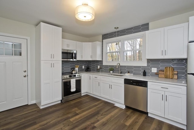 kitchen with stainless steel appliances, white cabinets, light countertops, and a sink