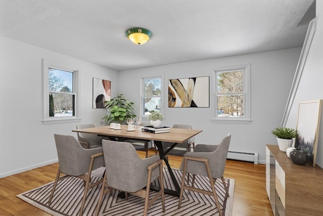 dining room with baseboard heating, baseboards, and light wood-style floors