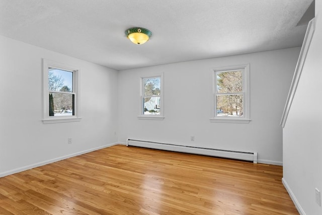 unfurnished room featuring a textured ceiling, light wood-style flooring, baseboards, and a baseboard radiator